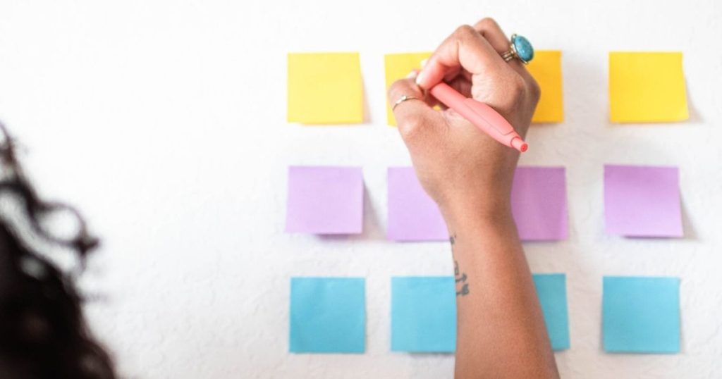 Woman writing affirmations for job interviews on post it notes