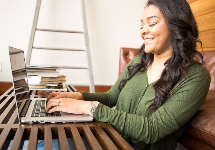 Smiling woman typing a resume on her computer