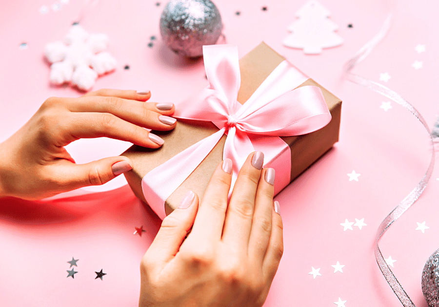 23 unique gift ideas for coworkers person unwrapping pink bow on box